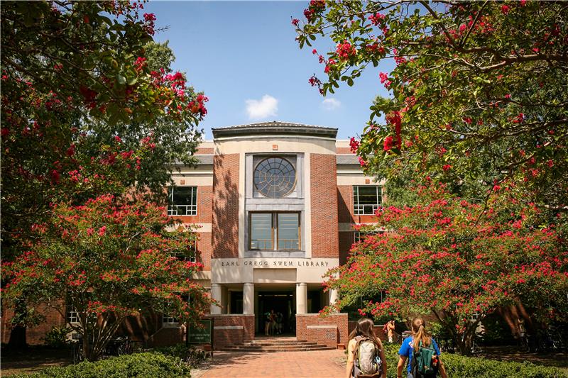 Photo of the entrance of Earl Greg Swem Library, characterized by red brick, ornate glass features, and cream pillars.