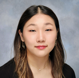 Headshot photo of young woman with shoulder length dark hair smiling softly and looking at the camera.
