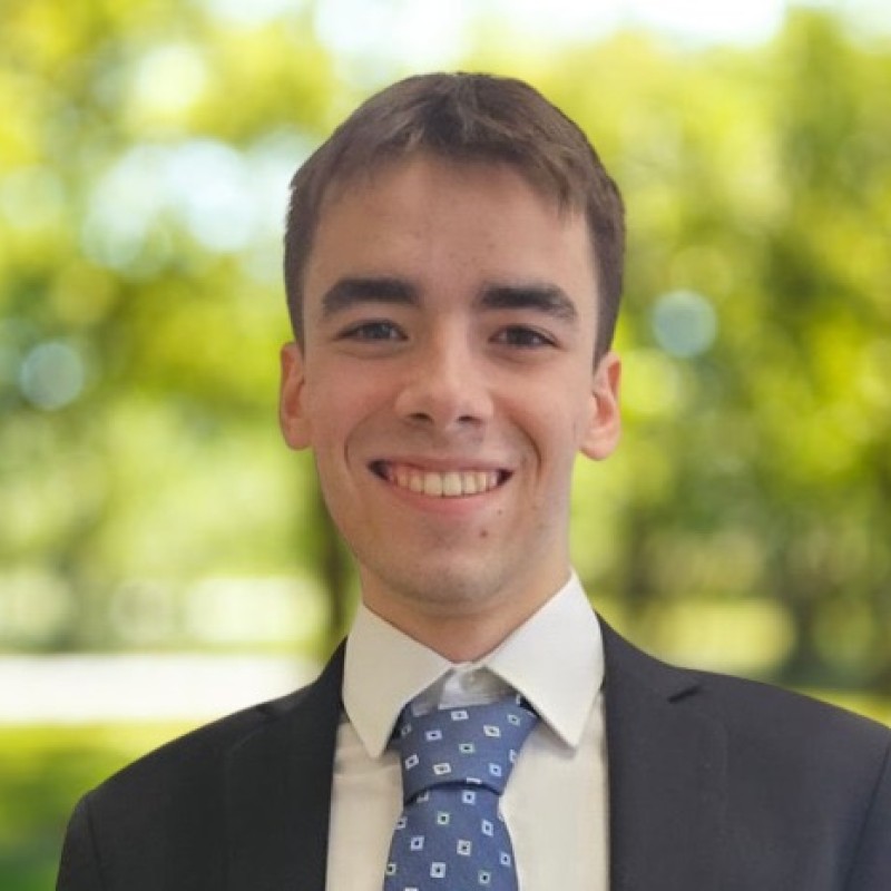Photo of the author wearing blue jacket, white shirt, and blue patterned tie, smiling and facing the camera.